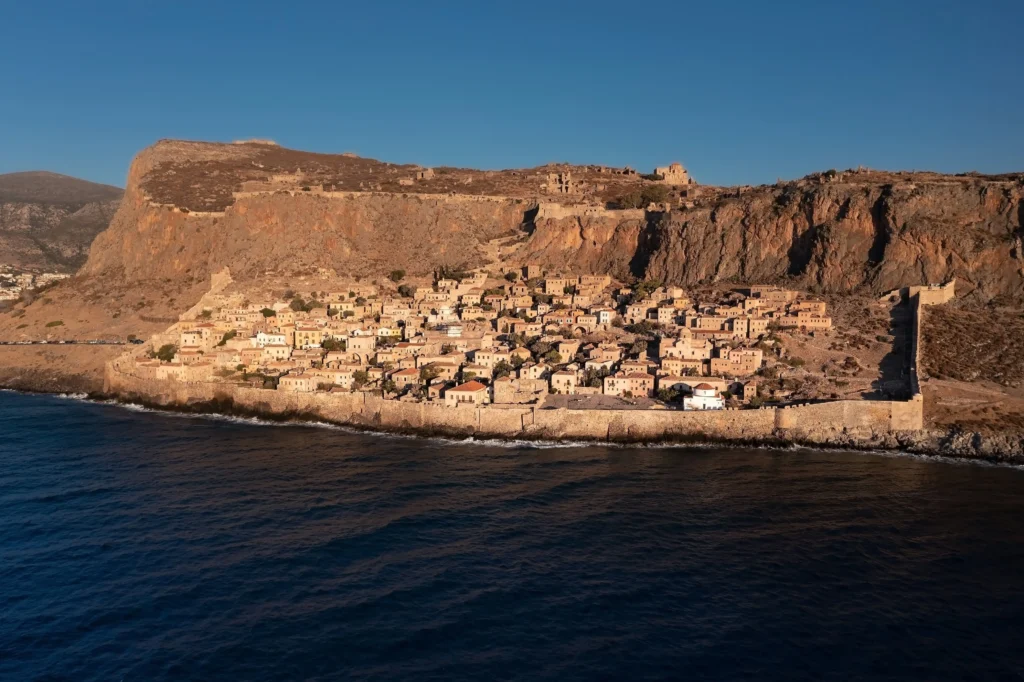Aerial view of the ancient city and fortress wall of Monemvasia along the shore during sunrise in Greece
